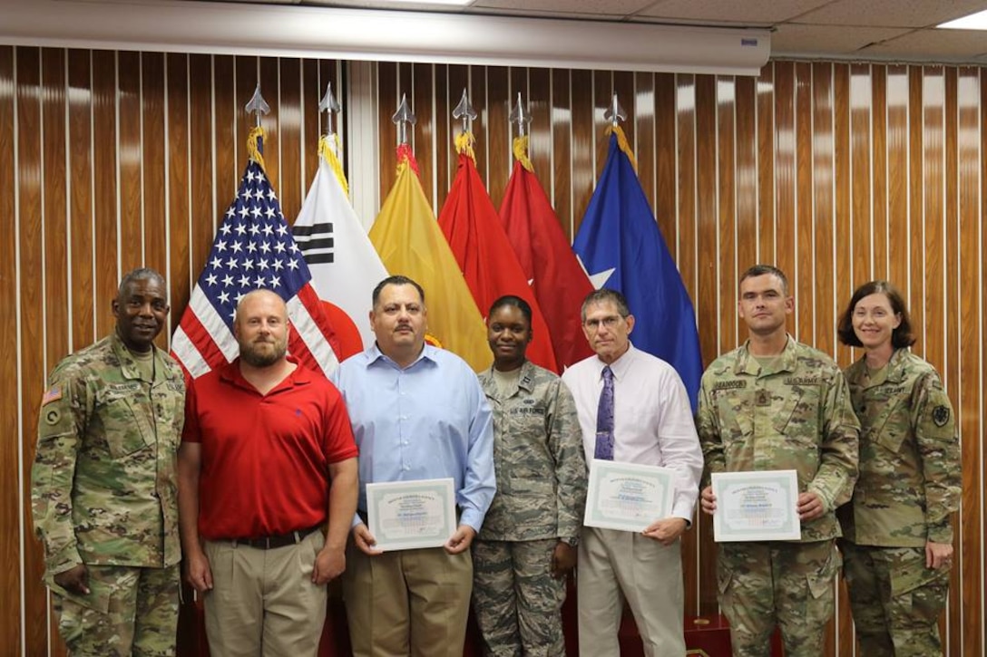 Group facing viewer, some holding certificates