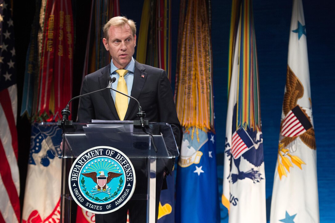 The deputy defense secretary speaks on stage from behind a podium.