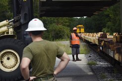 U.S. Marine Lance Cpl. Matthew Wright, foreground, Navy Munitions Command Atlantic Unit Charleston Marine Corps Liaison Office member, observes Vernon Bankston, background, 628th Logistics Readiness Squadron ground transportation braker switchman, as he communicates with a train conductor during a munitions container download at Joint Base Charleston’s Naval Weapons Station Aug. 21. Marines attached to the NMC’s Marine Corps Liaison Office are responsible for inspecting munitions containers to ensure they are receiving quality items that are safe to use. These Marines work alongside NMC civilians and members of the U.S. Air Force 628th LRS during the download of containers in preparation for transport to their final destination.