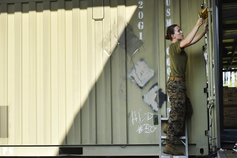 U.S. Marine Sgt. Karissa Greer, Naval Munitions Command Marine Corps Liaison Office member, takes informational placards off of unloaded munitions containers during an inventory inspection at the Joint Base Charleston Weapons Station, S.C., Aug. 23. Marines attached to the NMC’s Marine Corps Liaison Office are responsible for inspecting munitions containers to ensure they are receiving safe quality items during the download. These Marines work alongside NMC civilians and members of the U.S. Air Force 628th Logistics Readiness Squadron to prepare them for transport to their final destination.