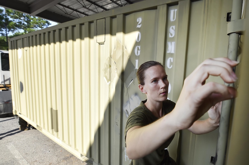 U.S. Marine Sgt. Karissa Greer, Naval Munitions Command Marine Corps Liaison Office member, takes informational placards off of unloaded munitions containers during an inventory inspection at the Joint Base Charleston Weapons Station, S.C., Aug. 23. Marines attached to the NMC’s Marine Corps Liaison Office are responsible for inspecting munitions containers to ensure they are receiving safe quality items during the download. These Marines work alongside NMC civilians and members of the U.S. Air Force 628th Logistics Readiness Squadron to prepare them for transport to their final destination. (U.S. Air Force photo by Staff Sgt. Christopher Hubenthal)