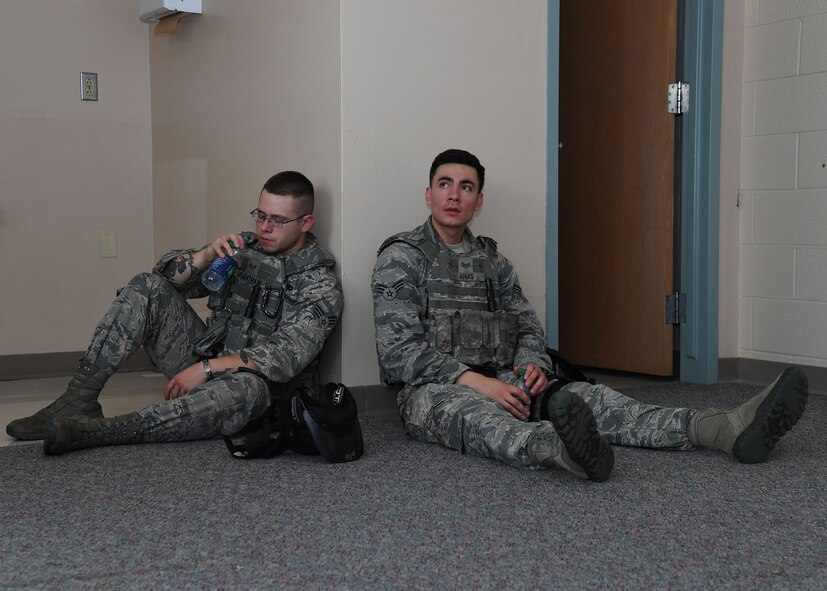 Senior Airmen Richard Arias and Jeren Grantham, Base Defense Operations Center controllers with the 319th Security Forces Squadron, take a water break after completing an active-shooter scenario during a training exercise at Carl Ben Eielson Elementary School Aug. 10, 2017 on Grand Forks Air Force Base, N.D. Groups of law enforcement officers, to include Airmen, took turns running through active-shooter scenarios set up by U.S. Customs and Border Protection supervisory agents. (U.S. Air Force photo by Airman 1st Class Elora J. Martinez)