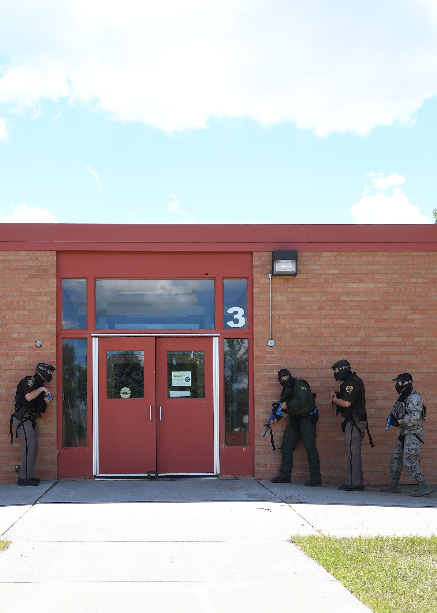 An Airman with the 319th Security Forces Squadron, far right, U.S. Customs and Border Protection agent, and officers with the Grand Forks Sheriff’s Department form up outside of Carl Ben Eielson Elementary School in preparation to enter an active-shooter scenario Aug. 10, 2017, on Grand Forks Air Force Base. The training exercise was held to allow the members to practice room clearing procedures, rear security and communication in order to apprehend potential shooters. (U.S. Air Force photo by Airman 1st Class Elora J. Martinez)