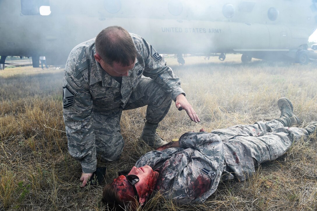 An airman provides medical aid to an airman on the ground.
