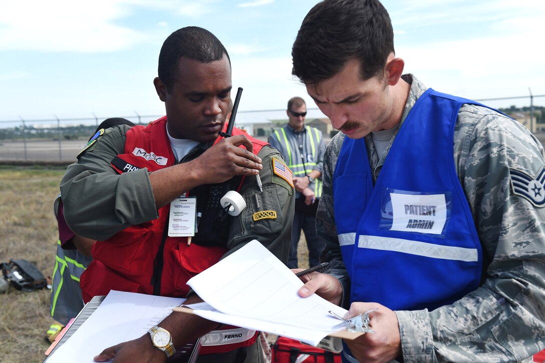 Two airmen discus the mock casualty roster in a field.