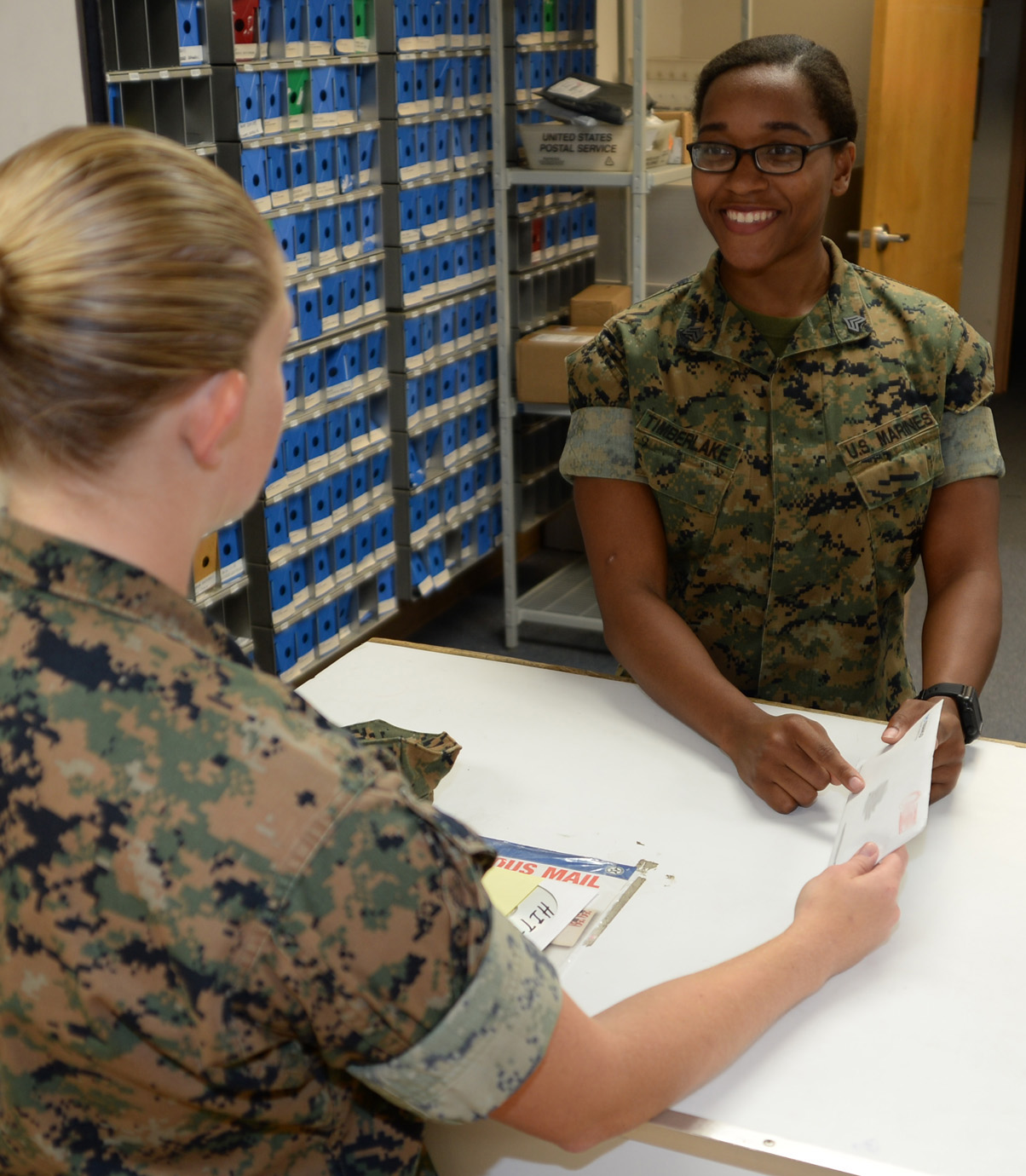 Sgt. Hope Timberlake, postal clerk, Post Office, Marine Corps Logistics Base Albany, assists a Marine with her mail, Aug. 21. She as meritoriously promoted to her current rank during a ceremony held here, Aug. 2.