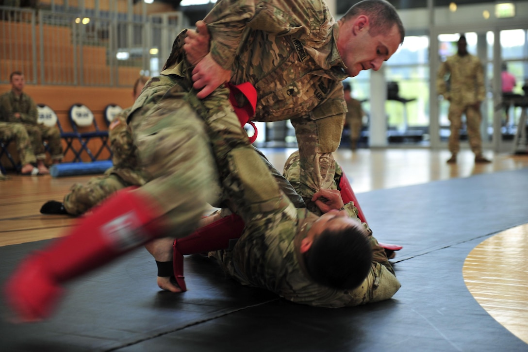 One soldier pins another to a gym floor during a combatives contest.