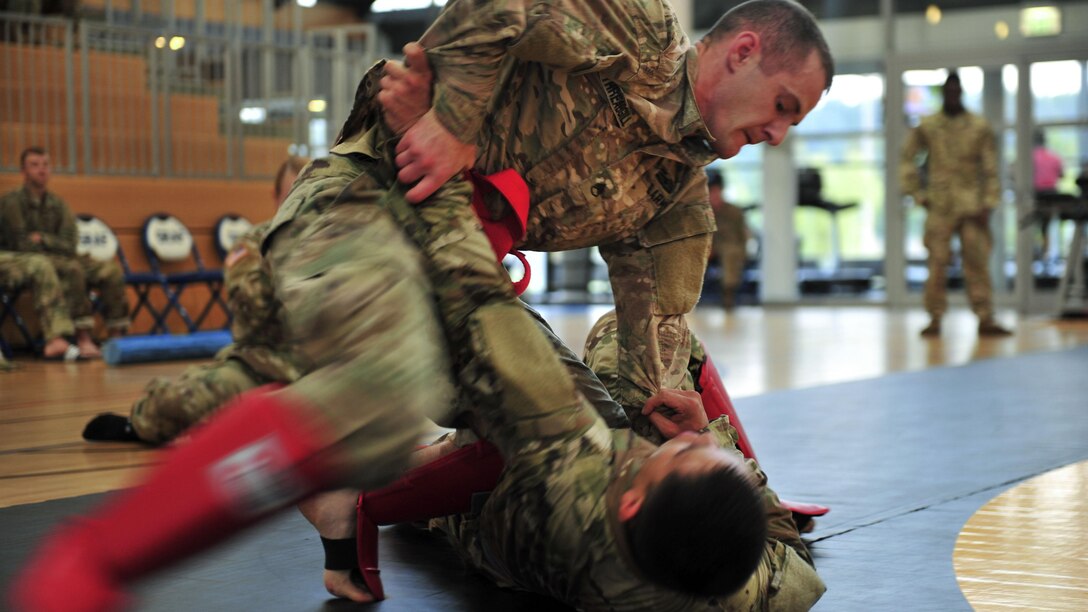 One soldier pins another to a gym floor during a combatives contest.