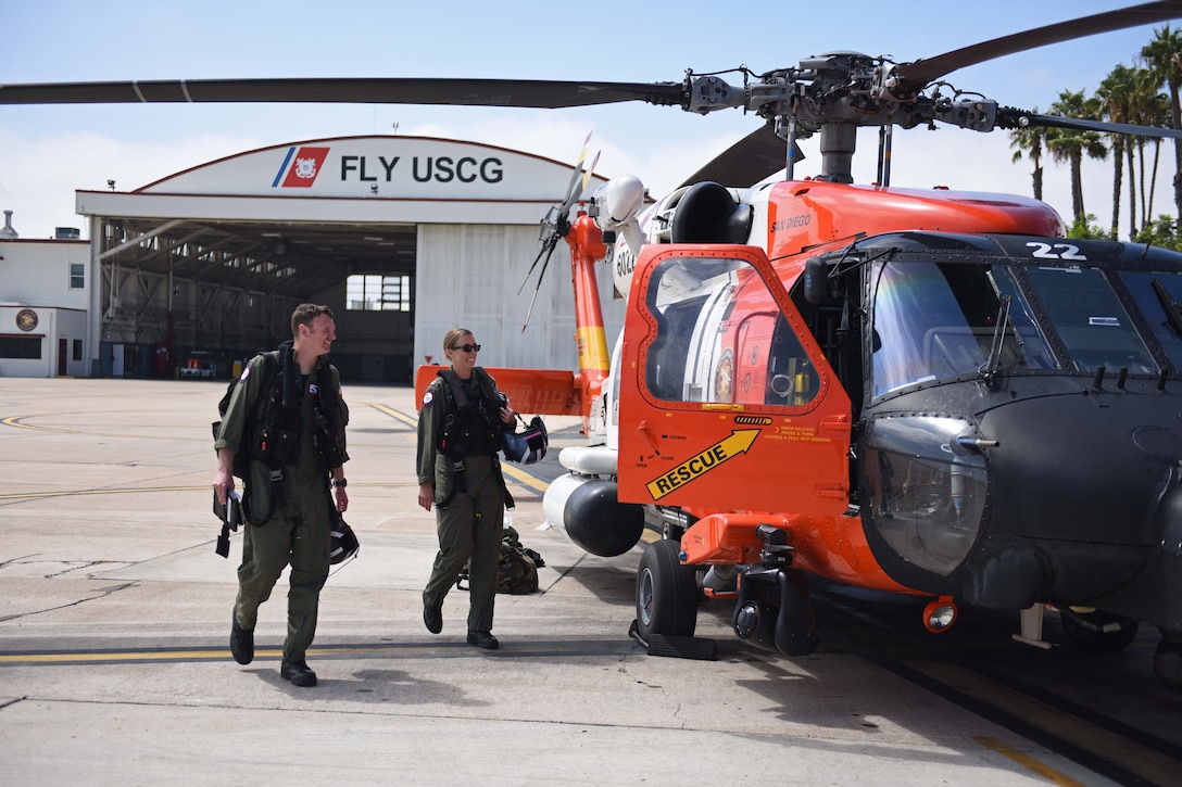 Two pilots walk toward a helicopter.