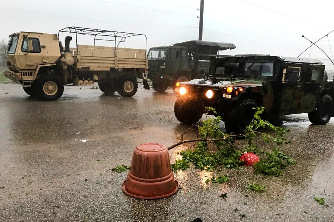 Three Texas Army National Guard vehicles patrol a street for damage.