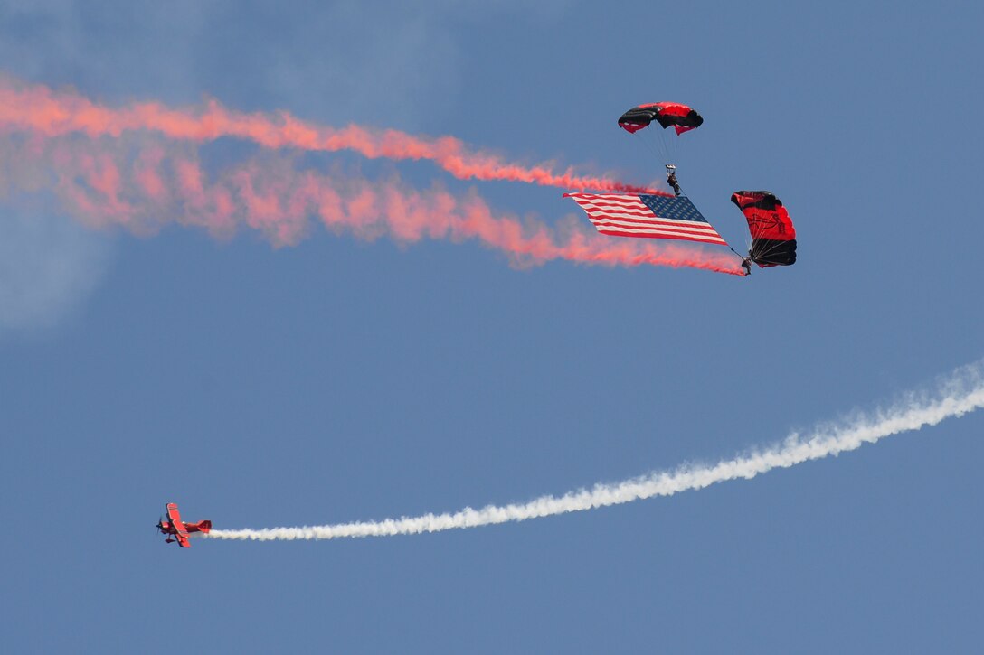 Members of the Black Daggers parachute with the American flag while ChefPitts flies in a corkscrew pattern around them Aug. 26, 2017, during the Thunder Over Dover Open House at Dover Air Force Base, Del. The Black Daggers are the U.S. Army Special Operations Command’s parachute demonstration team. (U.S. Air Force photo by Staff Sgt. Aaron J. Jenne)