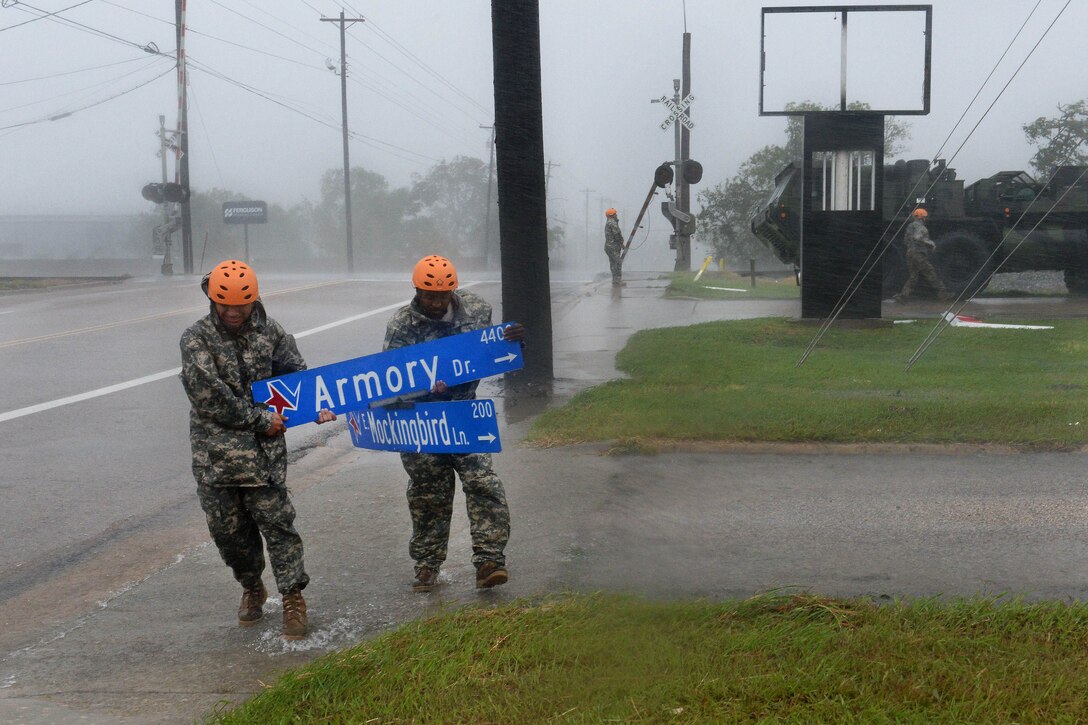 Texas Army National Guardsmen pick up a street sign during Hurricane Harvey.
