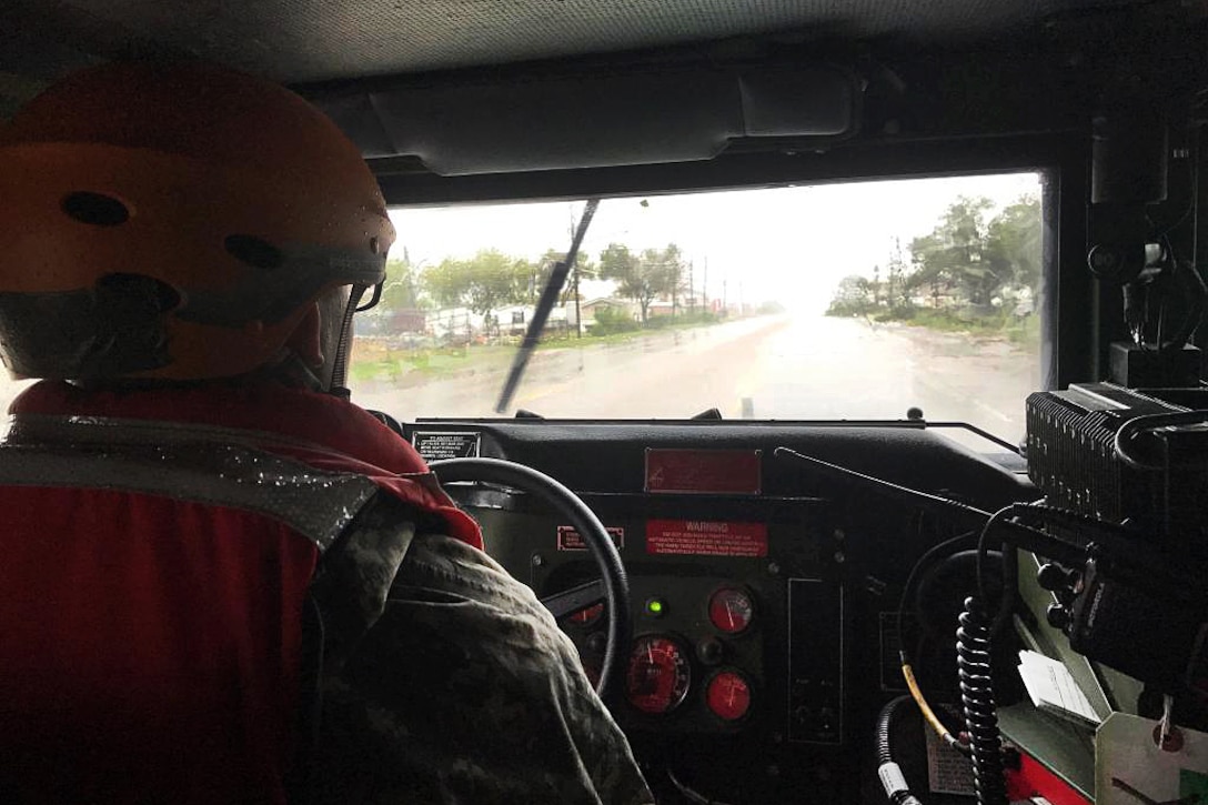 Texas Army National Guardsmen drive through flooded streets assessing damage.