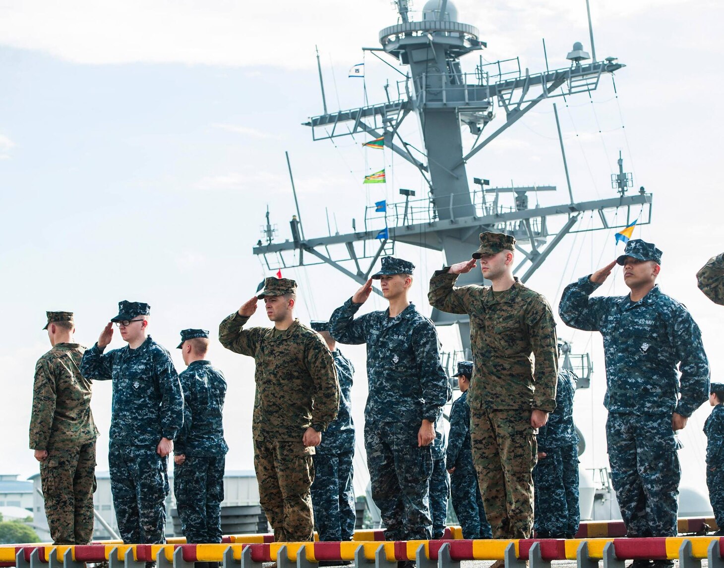 Sailors and Marines aboard USS America (LHA 6) render honors to the Arleigh Burke-class guided-missile destroyer USS John S. McCain (DDG 56) as the amphibious assault ship departs Singapore. America provided initial assistance to John S. McCain (DDG 56) following the destroyer’s collision on Aug. 21.