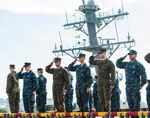 Sailors and Marines aboard USS America (LHA 6) render honors to the Arleigh Burke-class guided-missile destroyer USS John S. McCain (DDG 56) as the amphibious assault ship departs Singapore. America provided initial assistance to John S. McCain (DDG 56) following the destroyer’s collision on Aug. 21.