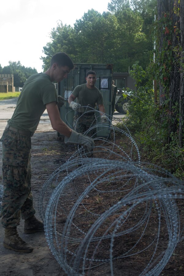 U.S. Marine Corps Lance Cpl. Samual F. Interlichia, left, a cyber network operator, and Cpl. Miguel A. Rivera, a food service specialist, both with the 26th Marine Expeditionary Unit (MEU), set up concertina wire for an entry control point during Realistic Urban Training (RUT) at Marine Corps Outlying Field Camp Davis-South, N.C., Aug. 16, 2017. RUT allows the 26th MEU Marines to gain operational experience working as a unit in an urban environment as preparation for an upcoming deployment at sea. (U.S. Marine Corps photo by Lance Cpl. Jered T. Stone)