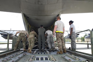 Airmen push a storage container onto a HC-130J Combat King II aircraft.