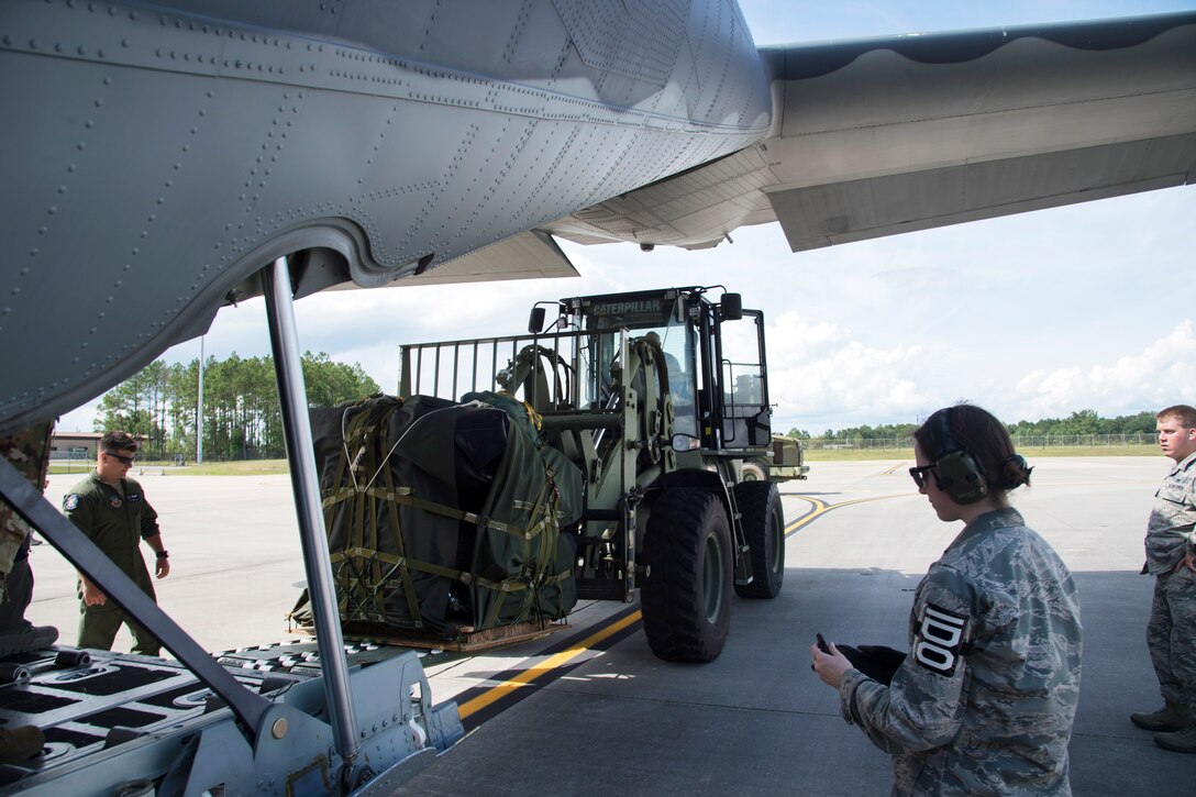 Airmen load gear and equipment onto a HC-130J Combat King II aircraft.