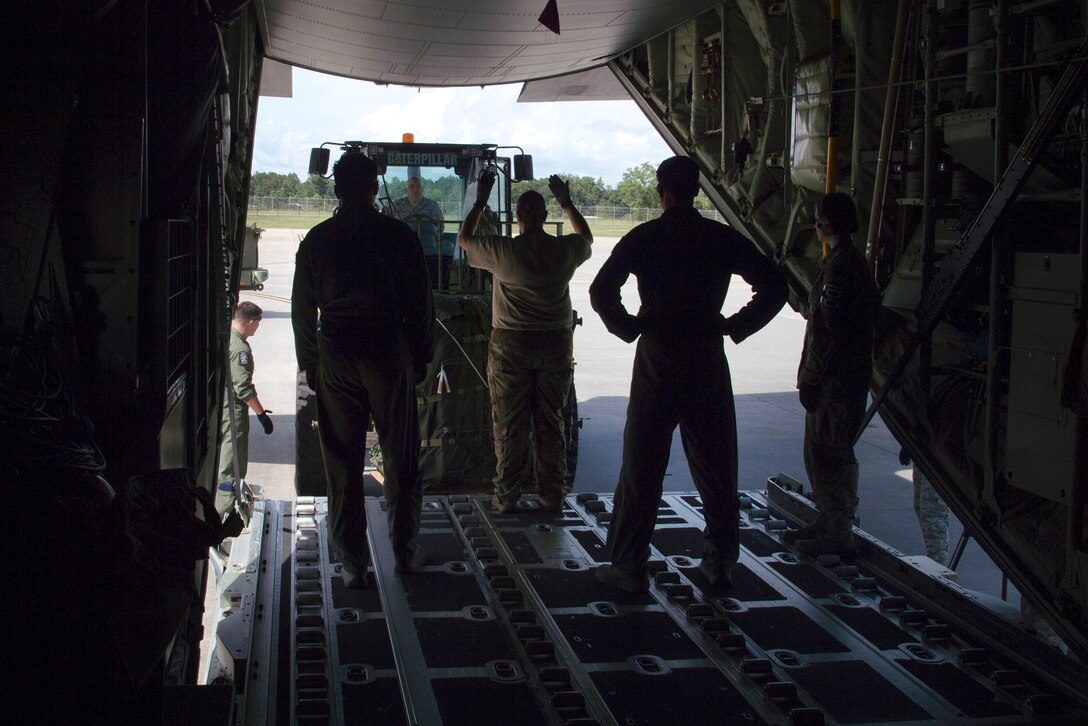 Airmen guide a forklift onto an HC-130J Combat King II aircraft traveling to Texas.