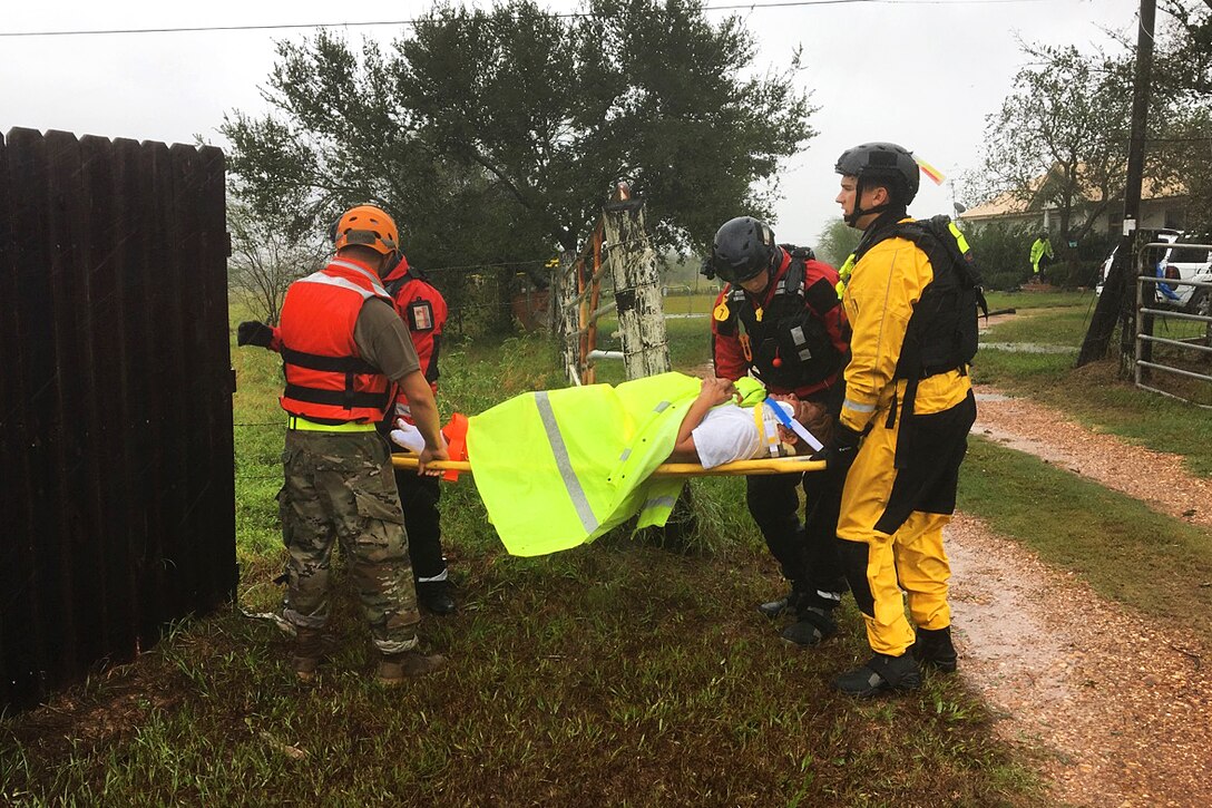 Texas National Guardsmen work with emergency responders by evacuating a resident on a stretcher.