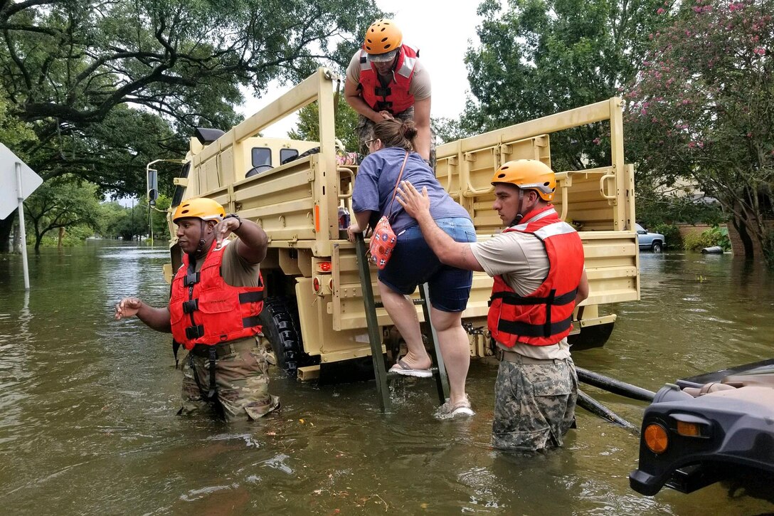 Texas National Guardsmen assist residents into a military vehicle during Hurricane Harvey flooding in Houston.