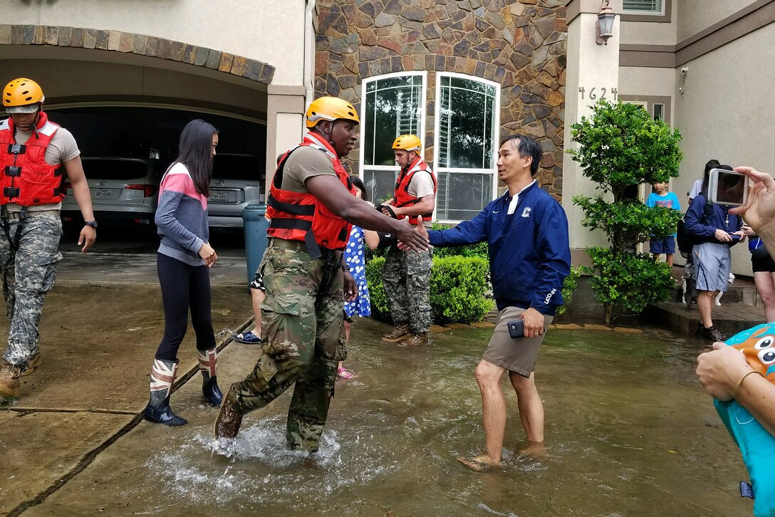 A Texas National Guardsman shakes hands with a resident after assisting his family.
