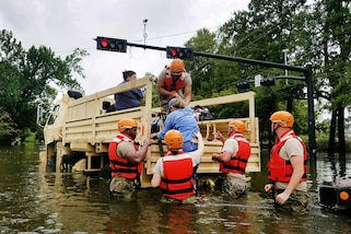 Texas National Guardsmen assist residents onto a military vehicle.
