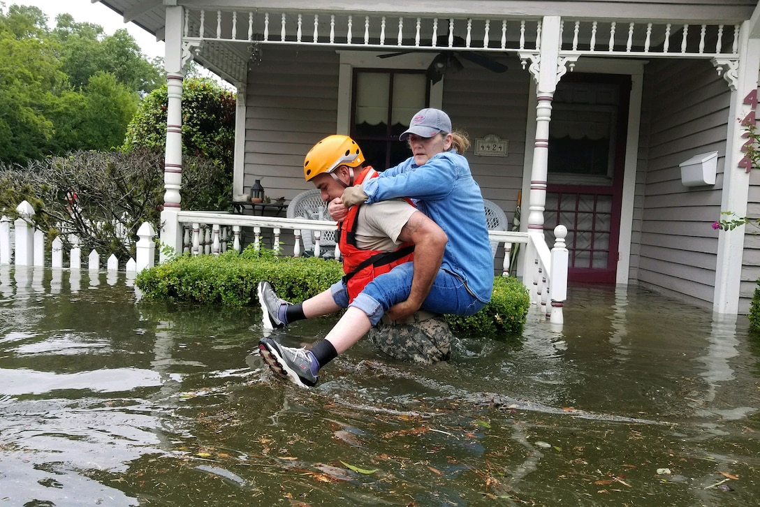 A Texas National Guardsman carry’s a resident’s from her home affected by flooding.