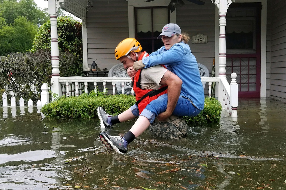 Guardsmen pull a boat through flooded streets.