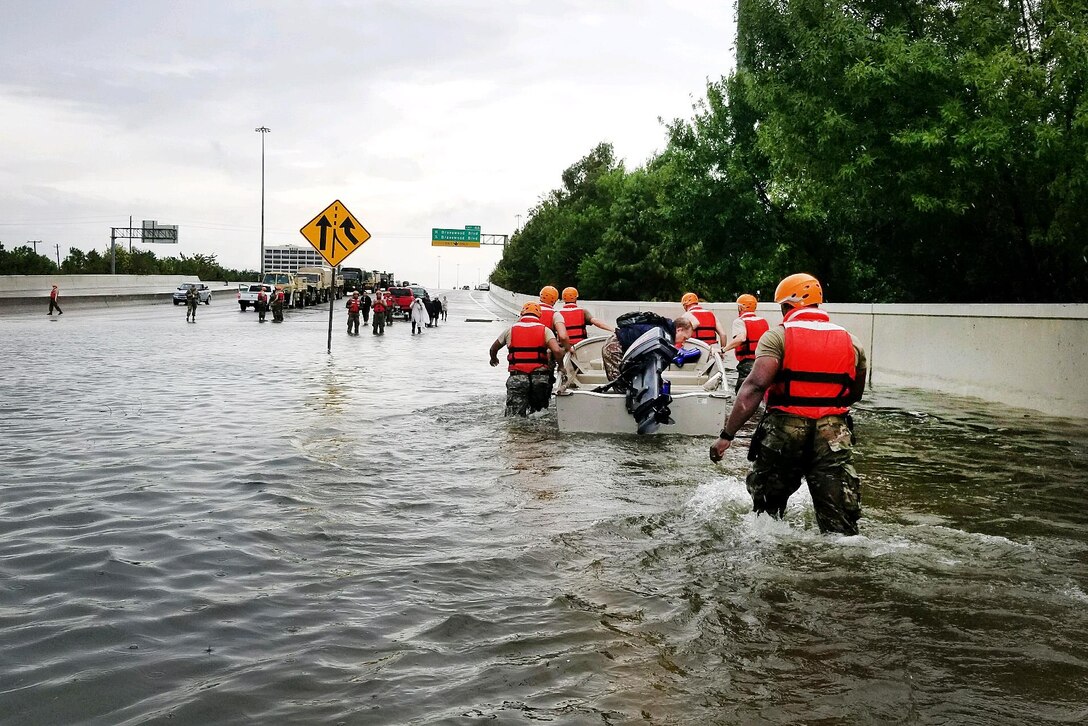 Texas National Guardsmen pull a boat with a resident displaced by flooding.