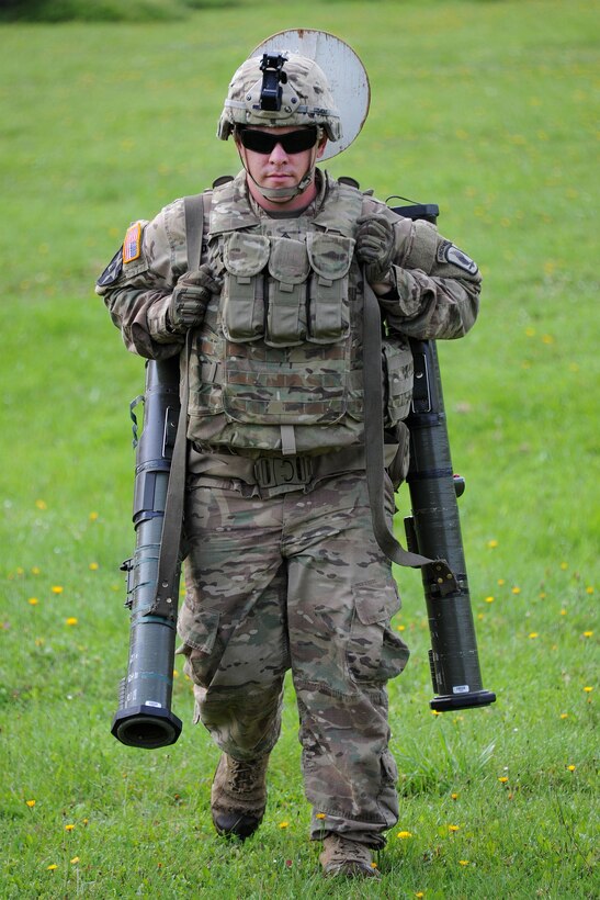 A soldier carries AT-4 rocket launchers during weapons familiarization