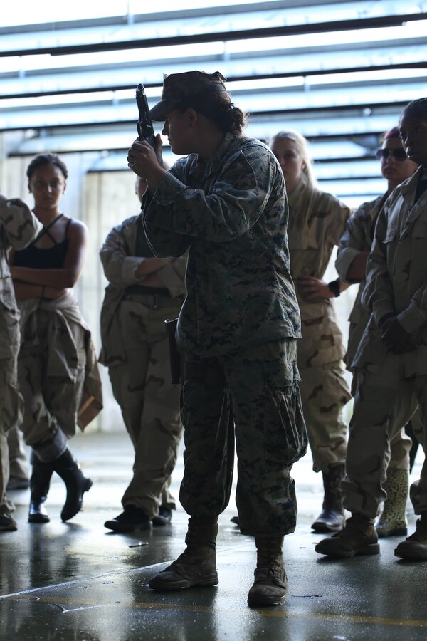 A U.S. Marine with the Female Engagement Team (FET), 26th Marine Expeditionary Unit (MEU), instructs proper pistol marksmanship techniques to a group of training event role players also with the 26th MEU, during Realistic Urban Training (RUT) at Stone Bay, N.C., Aug. 24, 2017. The event was part of a rehearsal by FET to enhance their training techniques as part of RUT, designed to provide the 26th MEU an opportunity to train in an unfamiliar environment in preparation for an upcoming deployment at sea. (U.S. Marine Corps photo by Cpl. Sylvia L. Tapia)