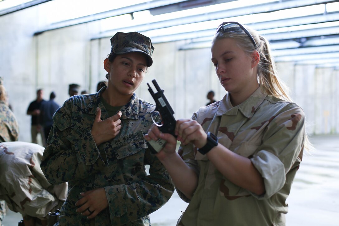 A U.S. Marine with the Female Engagement Team (FET), 26th Marine Expeditionary Unit (MEU), instructs proper pistol marksmanship techniques to a training event role player also with the 26th MEU, during Realistic Urban Training (RUT) at Stone Bay, N.C., Aug. 24, 2017.