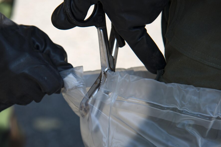 Airman 1st Class Shelby Staples, 347th Operations Support Squadron aircrew flight equipment technician, left, cuts the plastic boot cover from Capt. Chisom Ezeoke, 71st Rescue Squadron combat systems officer, during Aircrew Contamination Control Area training, Aug. 24, 2017, at Moody Air Force Base, Ga. ACCA training teaches aircrew how to remove and properly handle any contamination on their gear. (U.S. Air Force photo by Airman 1st Class Erick Requadt)