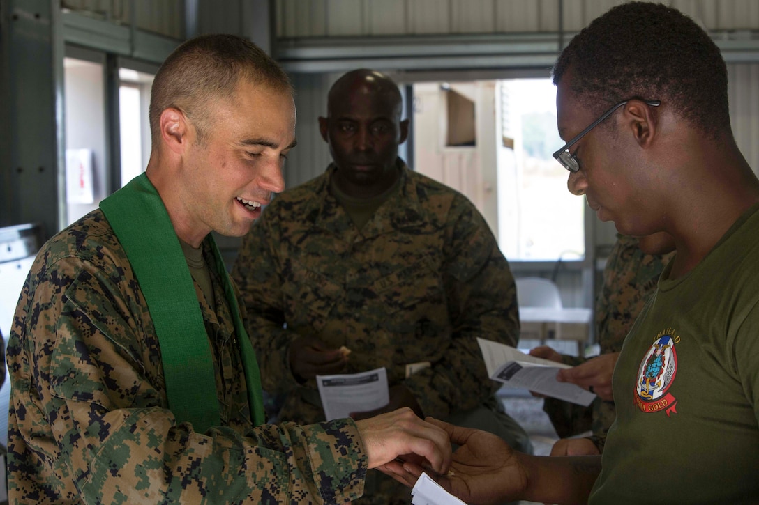 U.S. Navy Lt. Cmdr. John M. Mabus, the 26th Marine Expeditionary Unit (MEU) chaplain, passes out bread for communion to Marines during realistic urban training (RUT) at Camp Davis Training Area, N.C., Aug. 20, 2017.