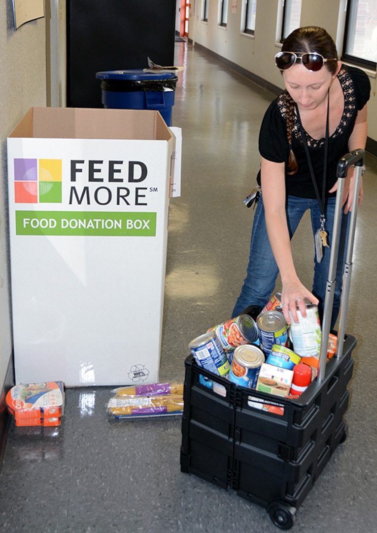 Jami Zanetta loads canned foods into a cart to take to Feedmore.
