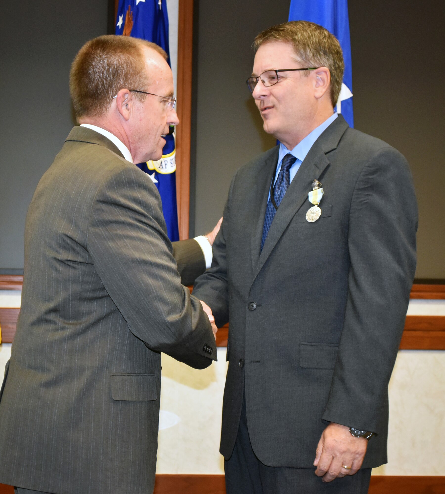Jeffrey Allen, Air Force Sustainment Center executive director, congratulates Steven Alsup on receiving the Meritorious Civilian Service Award during a farewell ceremony for the AFSC Logistics Director Aug. 25 in the Anaconda Conference Room, Bldg. 3001.