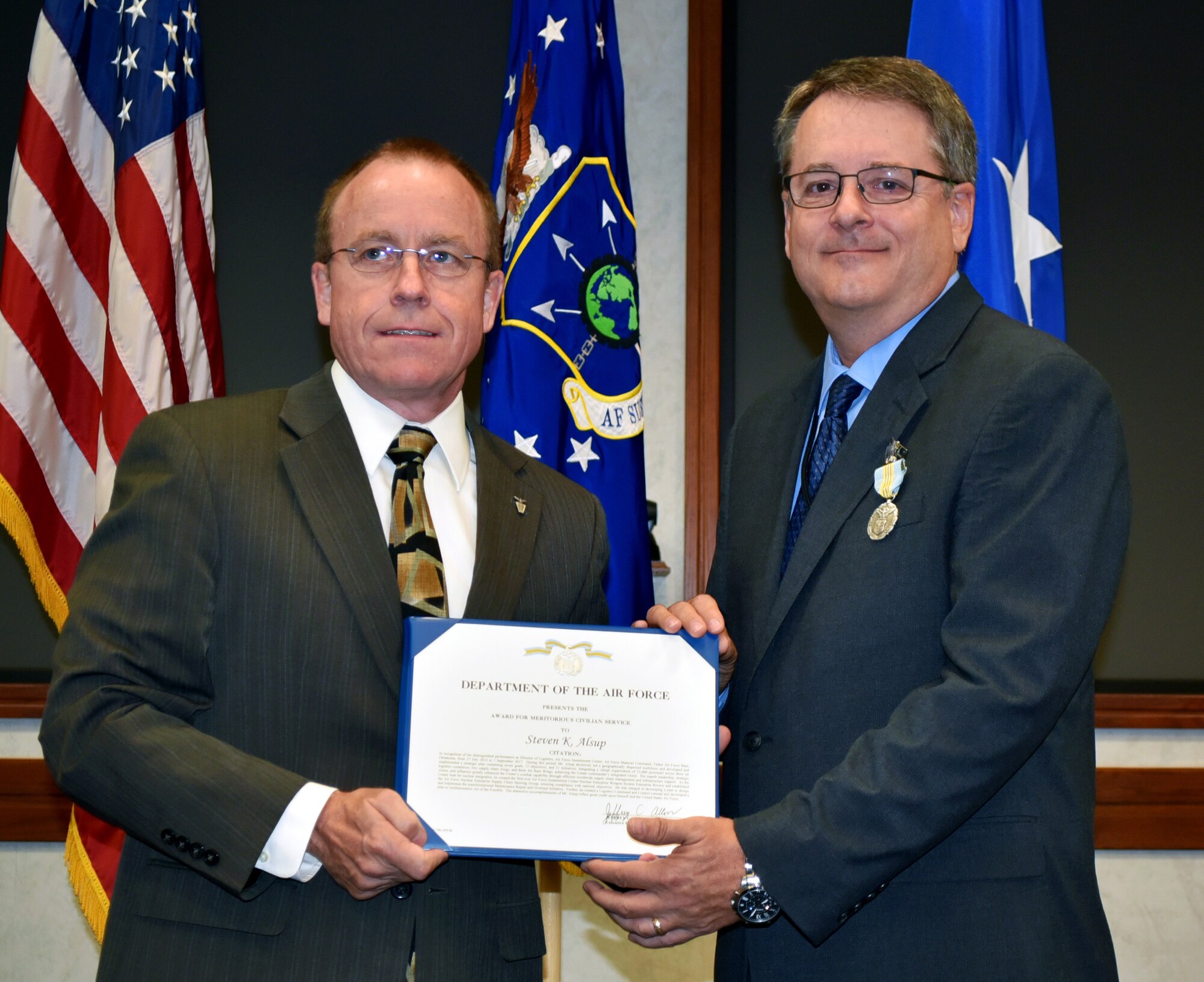 Jeffrey Allen, Air Force Sustainment Center executive director, presents Steven Alsup with the Meritorious Civilian Service Award during a farewell ceremony for the AFSC Logistics Director on Friday in the Anaconda Conference Room, Bldg. 3001.
