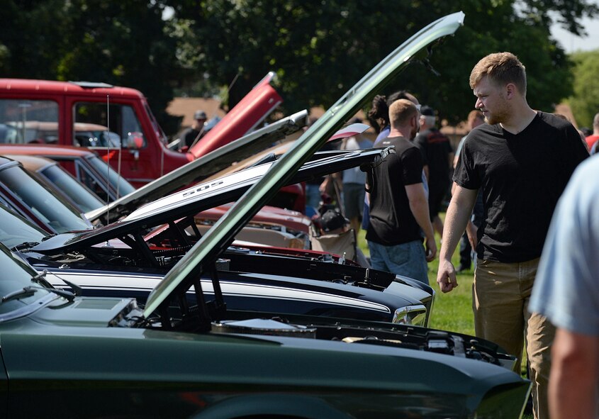 An enthusiast looks at all the horsepower being displayed under the hoods, during the annual Ogden Air Logistics Complex summer picnic and car show. (U.S. Air Force photo by Alex R. Lloyd)