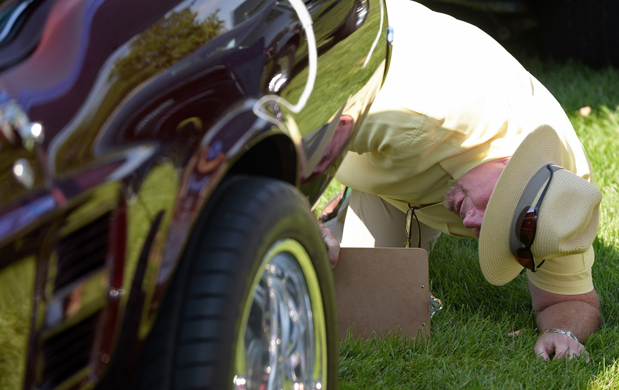 Douglas James, Ogden Air Logistics Complex, inspects a classic Ford Mustang while judging the vehicles assembled during the annual Ogden Air Logistics Complex car show. (U.S. Air Force photo by Alex R. Lloyd)