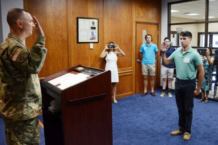 A man raises his right hand to enlist with people behind him.