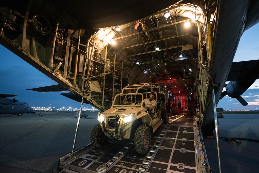 A military vehicle drives out of the rear of a military aircraft.