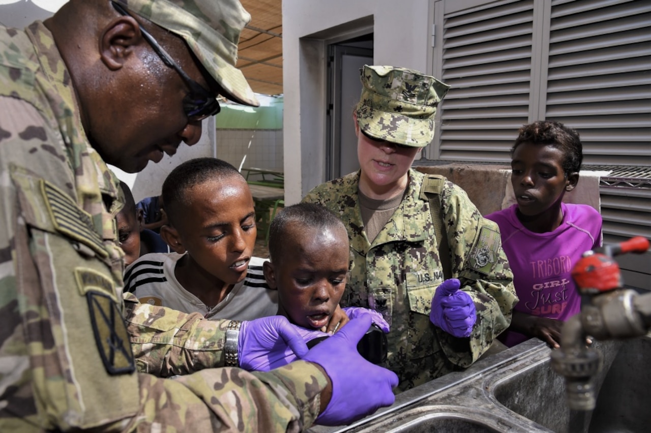 Navy Petty Officer 1st Class Samantha Ward, center, assigned to the Camp Lemonnier Emergency Medical Facility, and Army Maj. Donald Dais, 443rd Civil Affairs Battalion Functional Specialty Team Environmental Health officer in charge, test water samples.