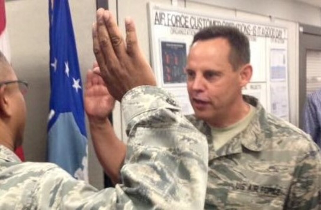 Airman in fatigues with hand raise to give oath, facing half-left as USAF officer administers oath.