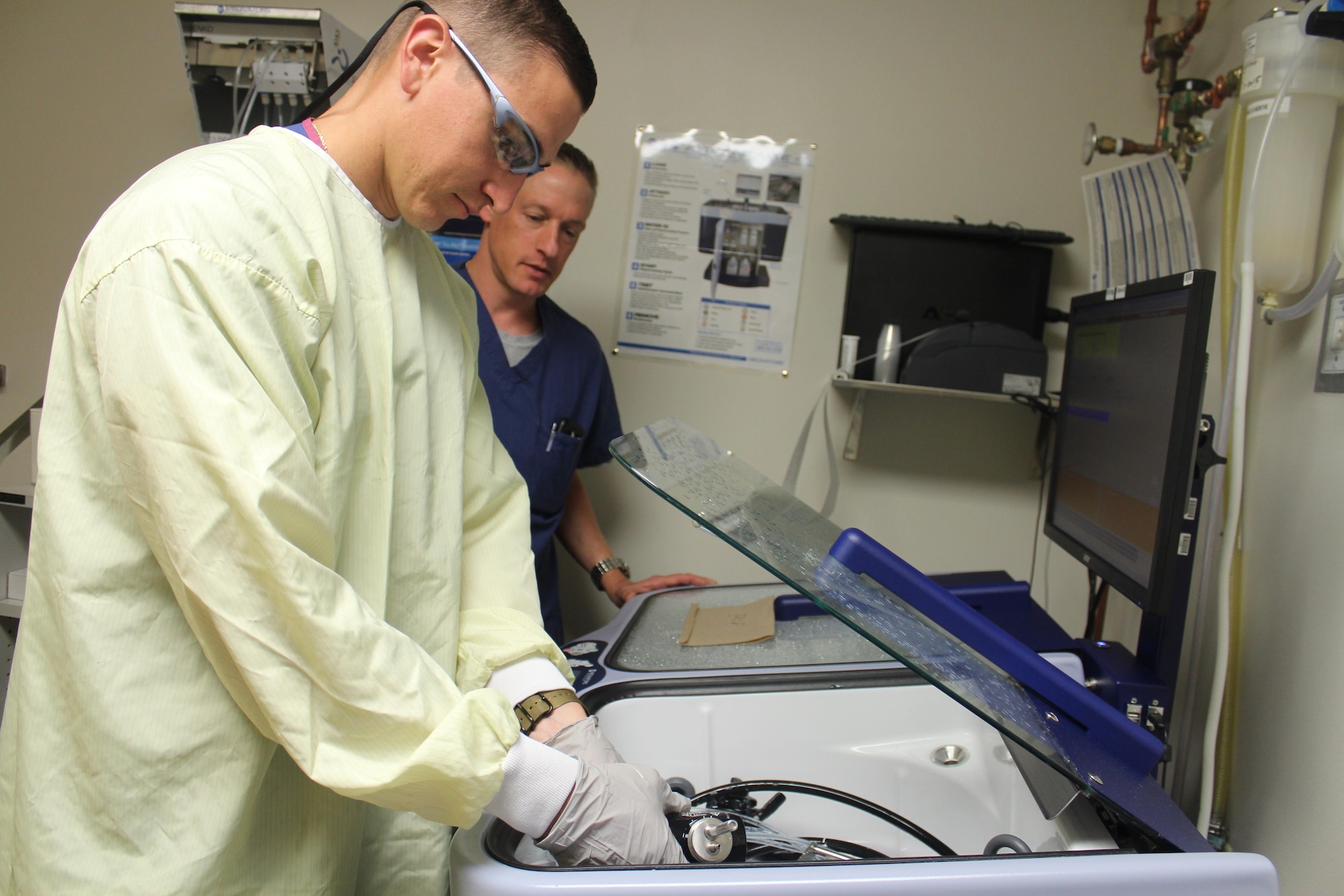 88th Medical Group chief of gastroenterology, Lt. Col Tristan Handler, looks over medical technician Senior Airman Kaleb Specht, as he sanitizes the equipment used in the clinic.