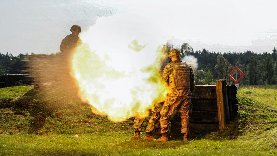 Soldiers fire a rocket launcher, causing a round ball of fire and smoke.