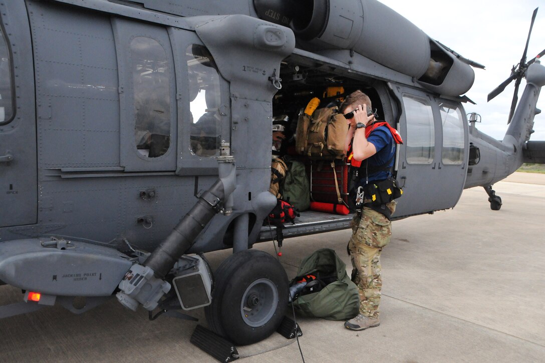 A man standing next to a helicopter adjust his headset before boarding.