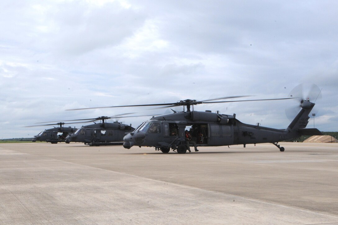 Three HH-60 Pave Hawk helicopters sit on a tarmac.