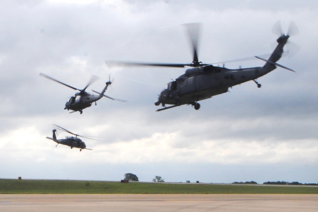 Three HH-60 Pave Hawk helicopters in the air over a tarmac.