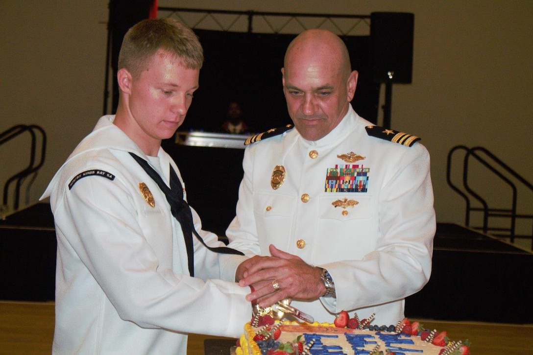 Lt. Cmdr. James Foster, executive officer, Marine Corps Security Force Battalion Kings Bay, and Seaman Apprentice Anthony Paruszkiewicz, master at arms, cut a slice of cake as the oldest and youngest sailors present at the Naval Submarine Base Kings Bay 6th Annual Master at Arms Ball, on Aug. 4 at the Omni Hotel in Amelia Island, Fl. The ball honored the 500 sailors who work aboard the submarine base to ensure its daily security. (Courtesy photo by Lance Cpl. Karlin Canady/Released)